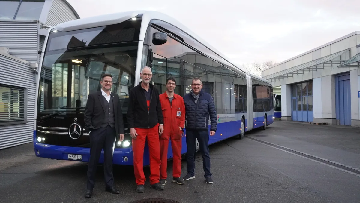 Vier Männer stehen vor einem Elektrobus.